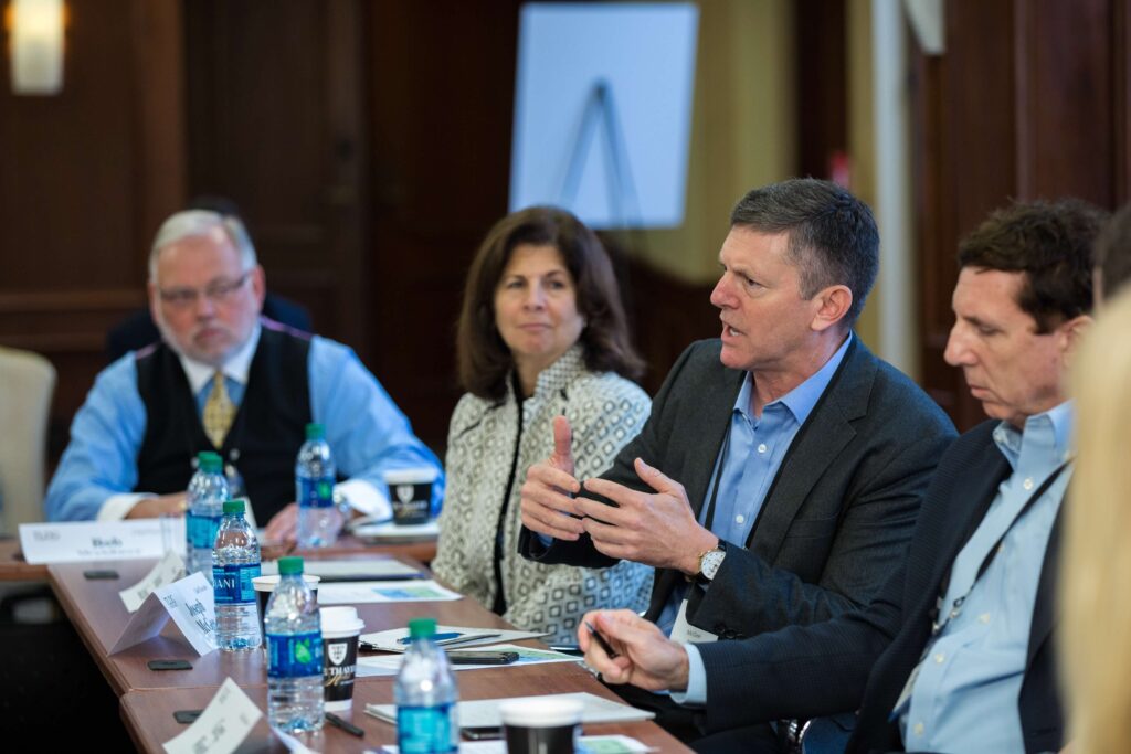 Four people, three men and one woman, in a conference room.